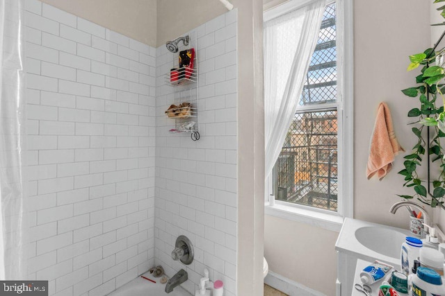 full bath with shower / tub combo, toilet, baseboards, and a sink