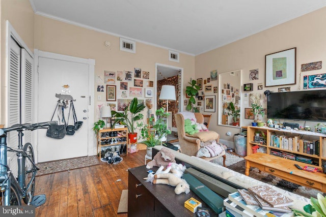 living area with hardwood / wood-style floors, visible vents, and ornamental molding