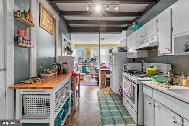 kitchen with white cabinets, light countertops, under cabinet range hood, beam ceiling, and white appliances
