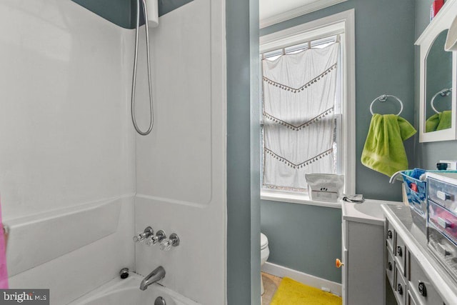 bathroom featuring vanity, a wealth of natural light, toilet, baseboards, and  shower combination