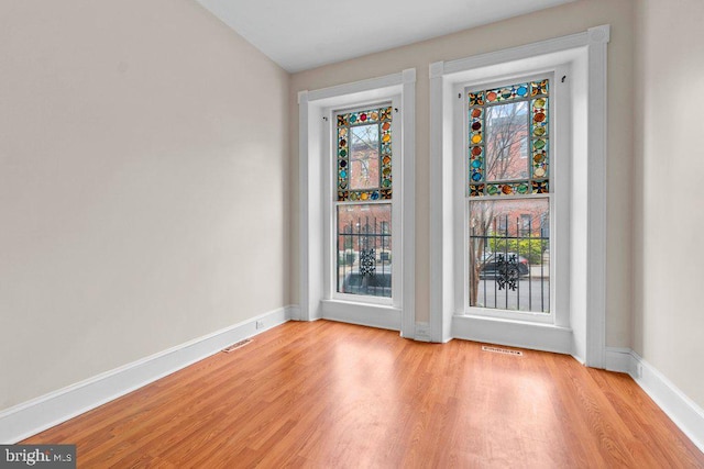 empty room featuring visible vents, light wood-type flooring, and baseboards