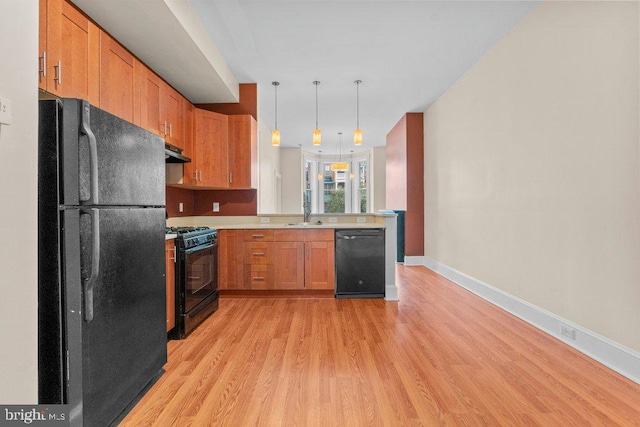 kitchen featuring light wood-style floors, light countertops, baseboards, black appliances, and under cabinet range hood