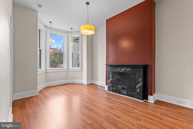 unfurnished living room with baseboards, wood finished floors, and a fireplace