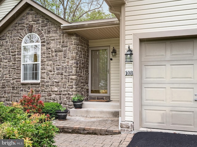 entrance to property featuring stone siding and a garage