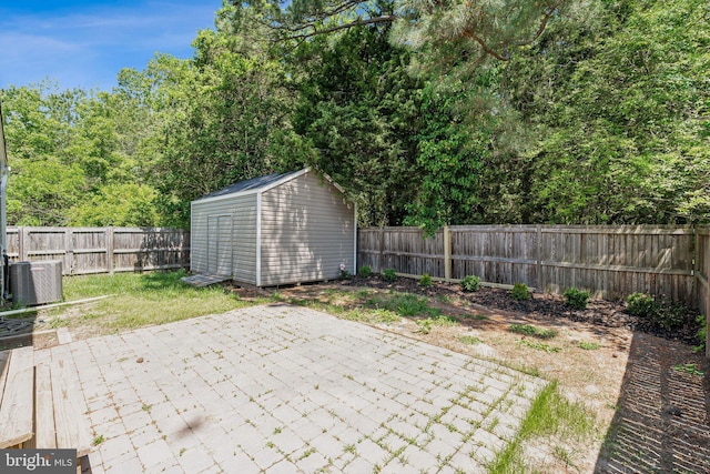 view of patio featuring a fenced backyard, a shed, an outbuilding, and central AC