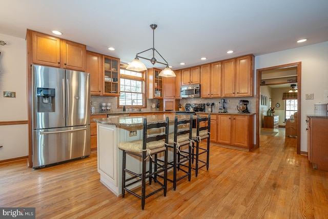 kitchen with a sink, light wood-style flooring, appliances with stainless steel finishes, and a healthy amount of sunlight