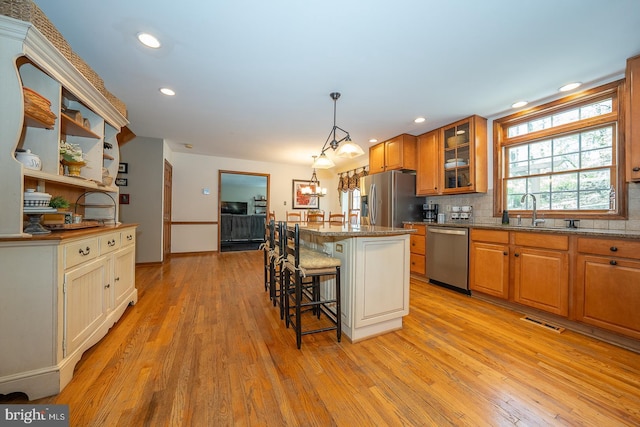 kitchen with visible vents, brown cabinetry, a breakfast bar area, a sink, and appliances with stainless steel finishes