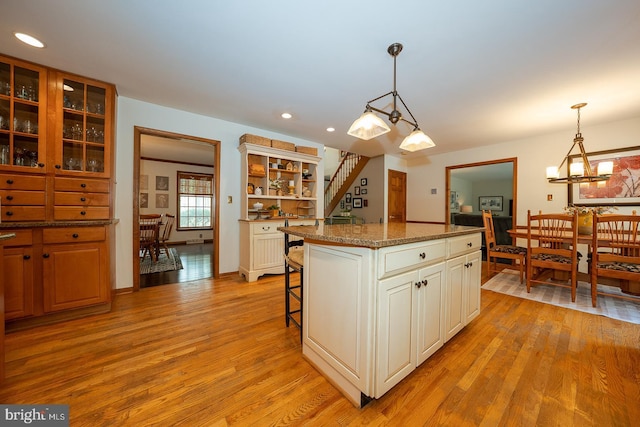 kitchen with open shelves, light wood finished floors, recessed lighting, a kitchen island, and glass insert cabinets