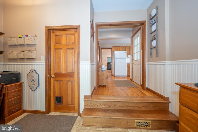 interior space with visible vents, wainscoting, light wood-style flooring, and a decorative wall