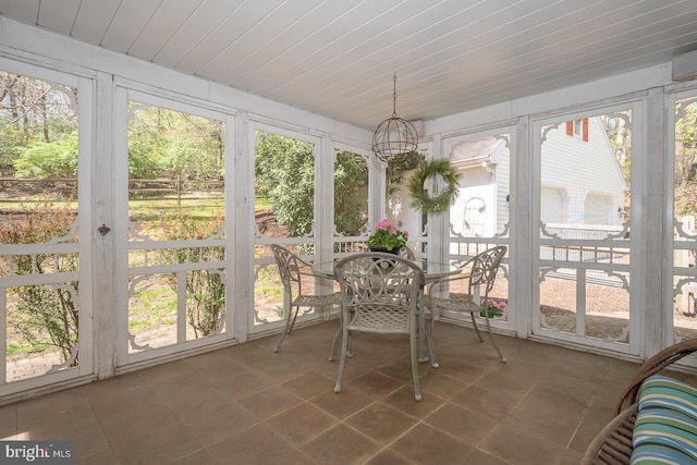 sunroom / solarium featuring tile patterned flooring, outdoor dining area, and a notable chandelier
