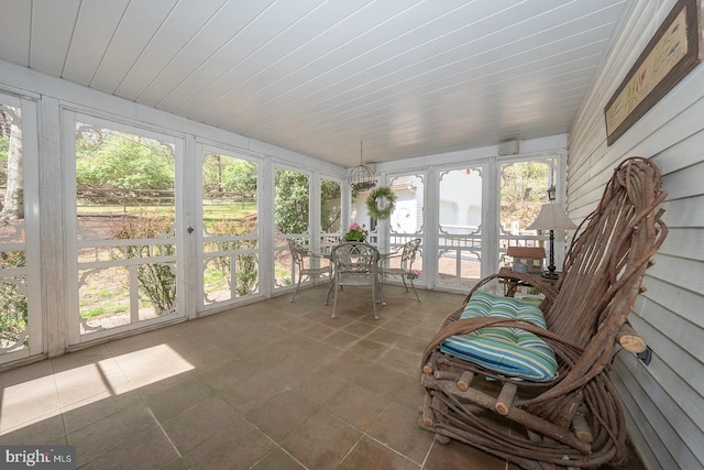 sunroom with outdoor dining area and a healthy amount of sunlight