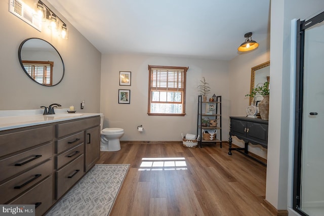 full bath featuring visible vents, wood finished floors, vanity, baseboards, and toilet