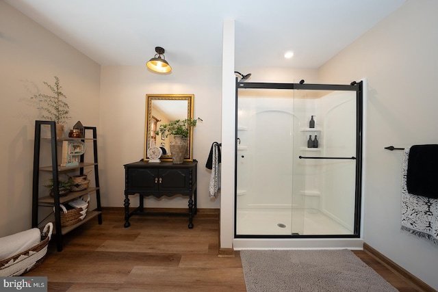 full bath with baseboards, a shower stall, and wood finished floors