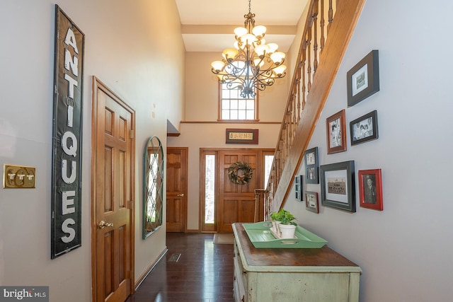 entryway featuring an inviting chandelier, dark wood-style flooring, a towering ceiling, baseboards, and stairway