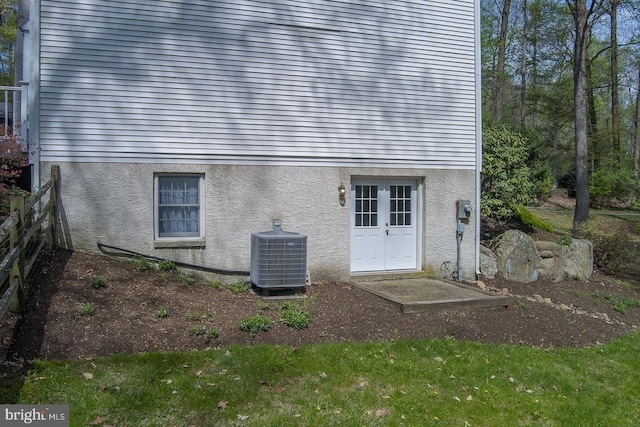 rear view of house with central AC unit and stucco siding