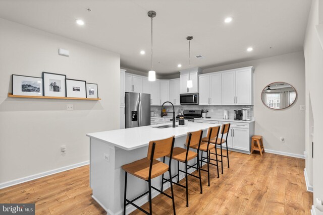 9451 James Macgowan Ln, Owings Mills, MD 21117 - kitchen with a sink, light wood-style floors, a kitchen bar, appliances with stainless steel finishes, and an island with sink