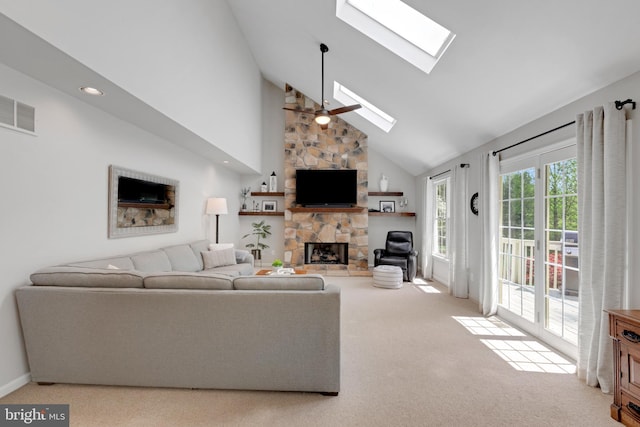 living room featuring a skylight, a stone fireplace, carpet flooring, visible vents, and high vaulted ceiling