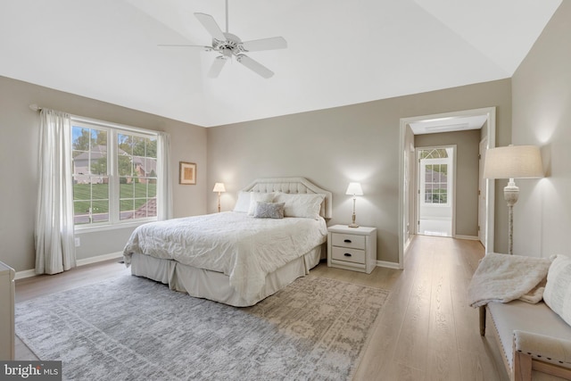 bedroom with light wood finished floors, vaulted ceiling, and multiple windows