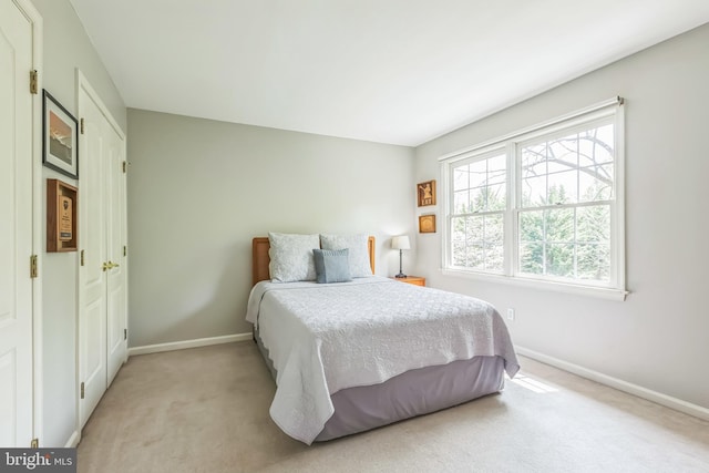 bedroom featuring light carpet and baseboards