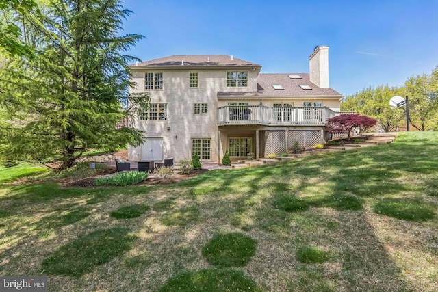 rear view of house featuring a lawn, a deck, stucco siding, and a chimney