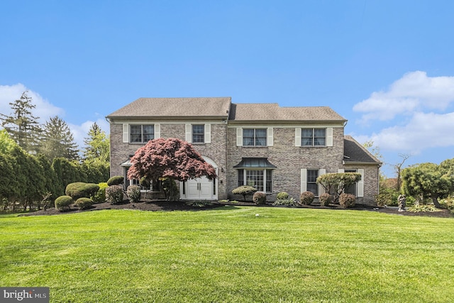 colonial house featuring brick siding and a front yard
