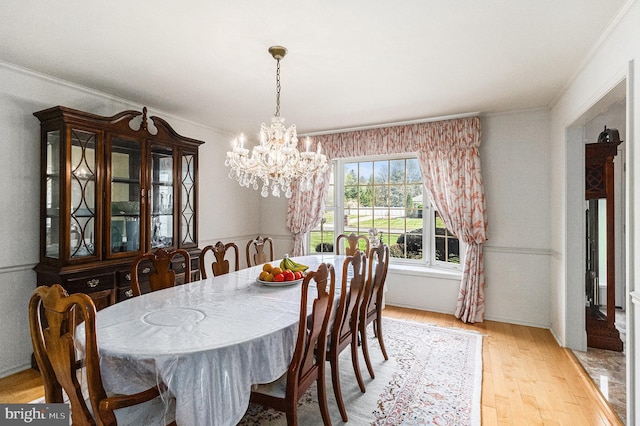 dining area with crown molding, light wood-style flooring, and a notable chandelier