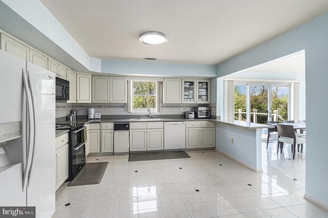 kitchen featuring a peninsula, light tile patterned flooring, white appliances, and tasteful backsplash