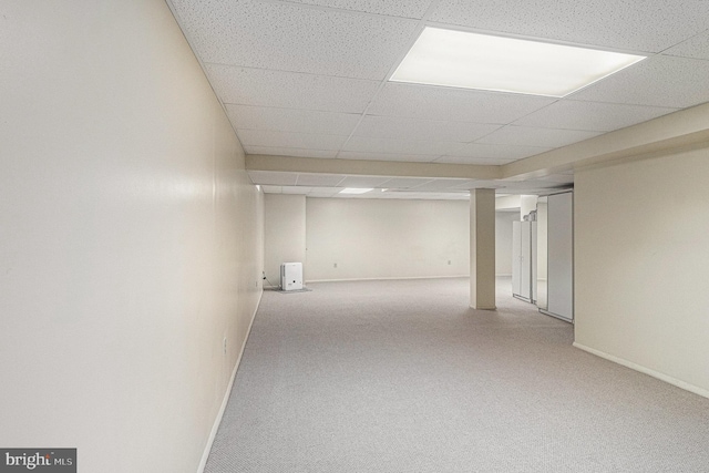 finished basement with baseboards, carpet flooring, and a drop ceiling