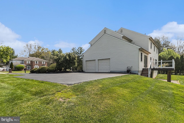 view of home's exterior featuring a garage, aphalt driveway, a wooden deck, and a yard