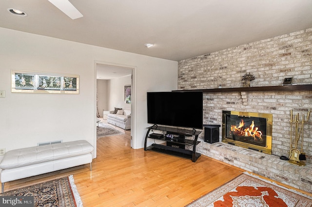 living area with a brick fireplace, recessed lighting, visible vents, and wood finished floors