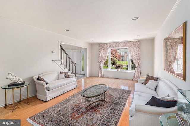 living area featuring baseboards, stairs, and wood finished floors