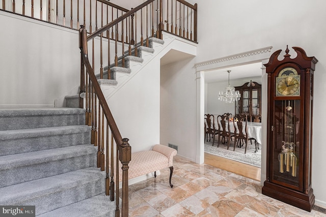 staircase with baseboards, a chandelier, visible vents, and a towering ceiling
