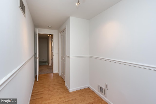 hall featuring baseboards, visible vents, and light wood-style flooring