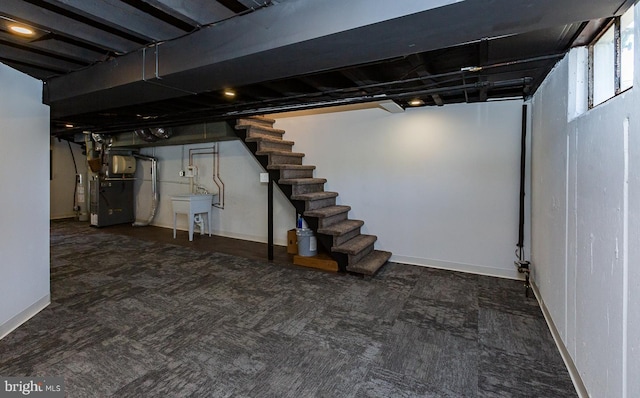 basement featuring carpet floors, baseboards, heating unit, and stairs
