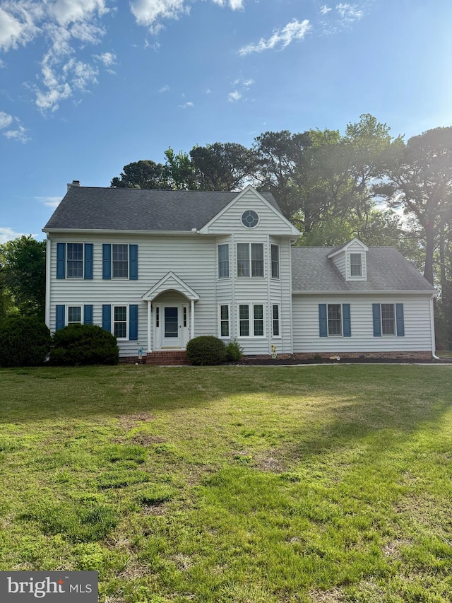 view of front facade with a shingled roof and a front lawn