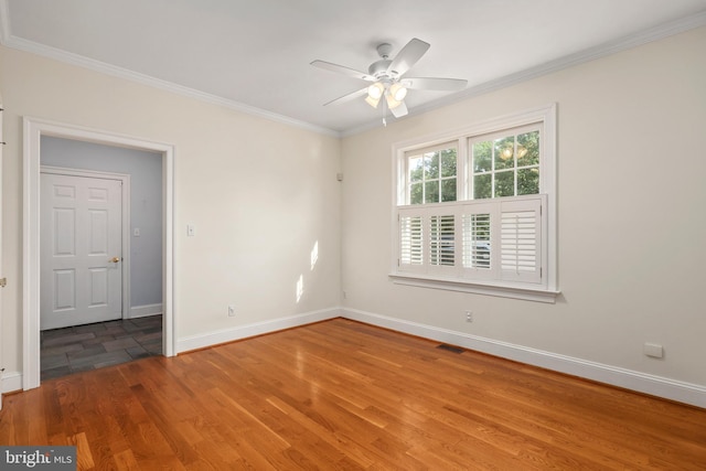 empty room with ceiling fan, visible vents, baseboards, ornamental molding, and wood finished floors