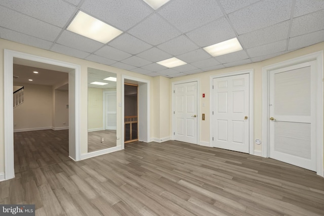 interior space with light wood finished floors, a paneled ceiling, stairway, and baseboards