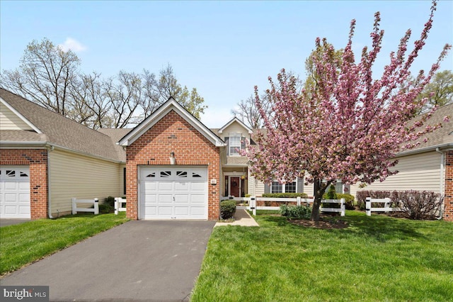 view of front of home with an attached garage, a front yard, brick siding, and aphalt driveway
