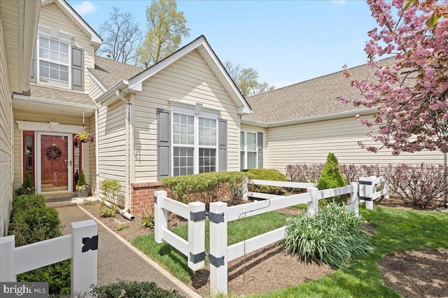 view of front of house featuring a fenced front yard, a shingled roof, and entry steps