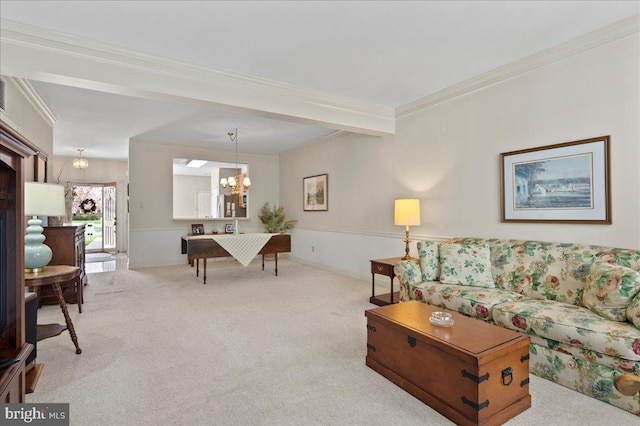 carpeted living room featuring crown molding, a notable chandelier, and a wainscoted wall