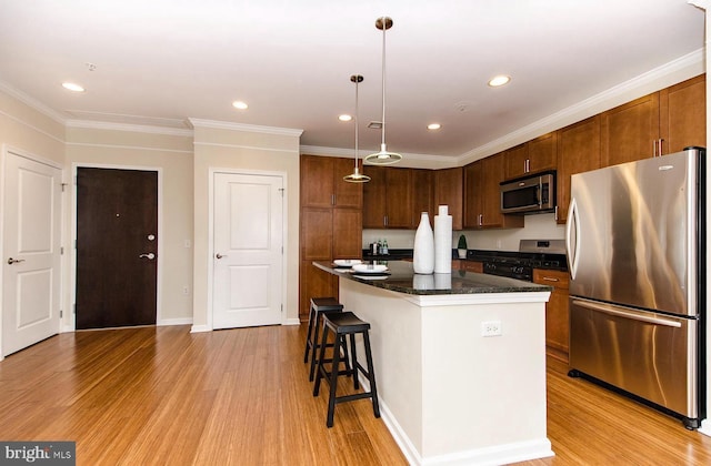 kitchen with a breakfast bar area, pendant lighting, a center island, stainless steel appliances, and light wood-style flooring