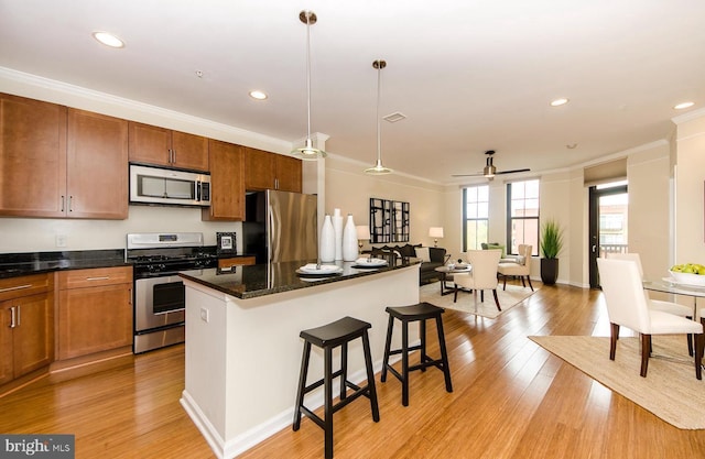 kitchen with crown molding, stainless steel appliances, a kitchen breakfast bar, and light wood-type flooring