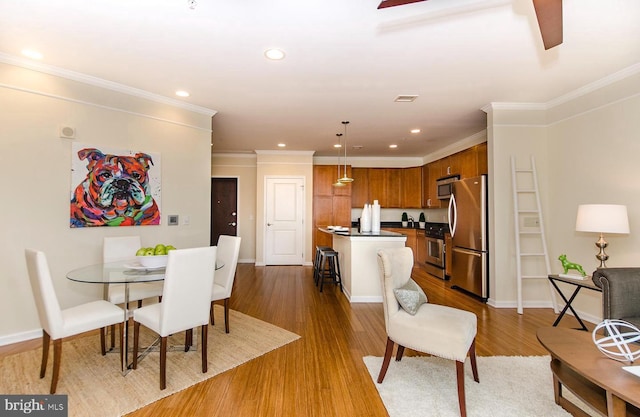 dining space with recessed lighting, ornamental molding, baseboards, and wood finished floors