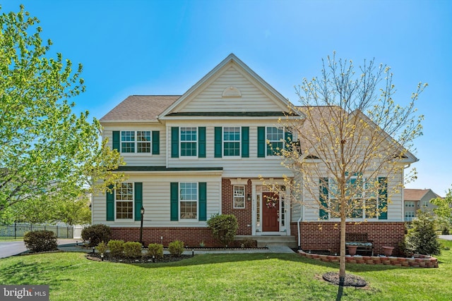 view of front of home featuring brick siding, fence, and a front yard