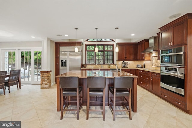 1253 Rowland Dr, Herndon, VA 20170 - kitchen featuring stainless steel appliances, wall chimney exhaust hood, decorative backsplash, light stone counters, and a kitchen bar