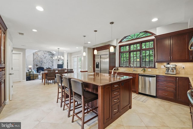 1253 Rowland Dr, Herndon, VA 20170 - kitchen with appliances with stainless steel finishes, open floor plan, decorative backsplash, a breakfast bar area, and a kitchen island with sink