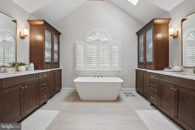1253 Rowland Dr, Herndon, VA 20170 - bathroom featuring baseboards, a freestanding tub, lofted ceiling, two vanities, and a skylight