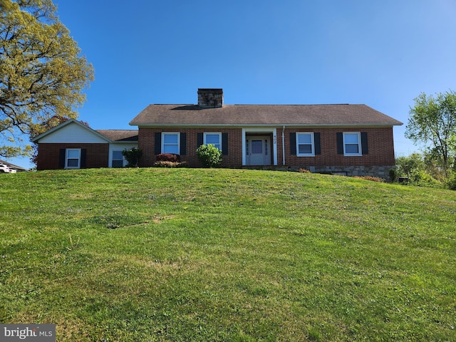 single story home featuring a front lawn, a chimney, and brick siding