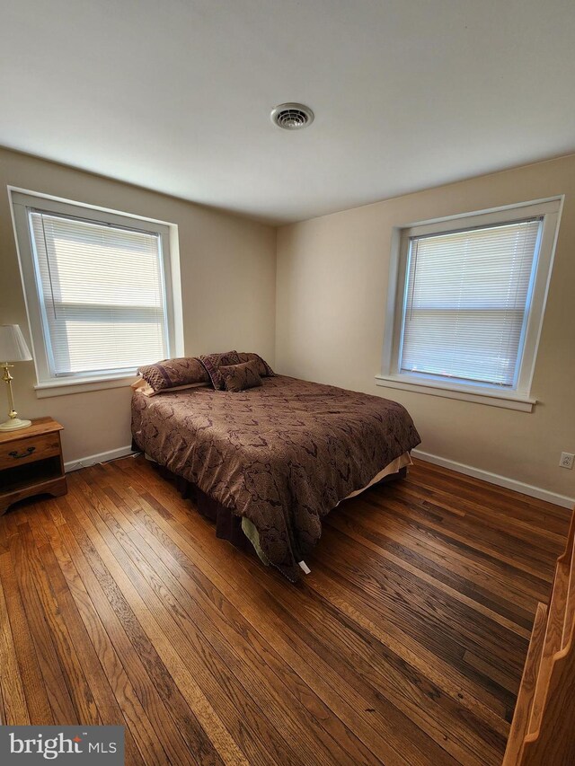 bedroom featuring visible vents, baseboards, and wood-type flooring