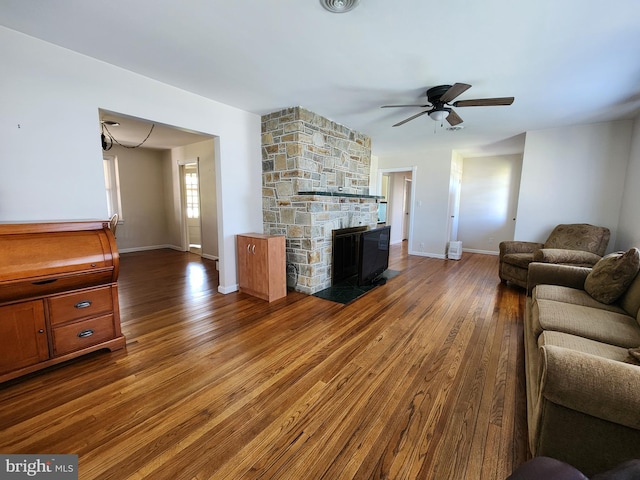 living room featuring wood finished floors, a ceiling fan, visible vents, and baseboards
